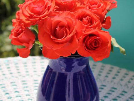 Purple vase with red roses on an outdoor patio table