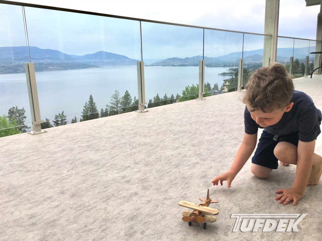 Child playing with toy on vinyl deck with view of lake in background