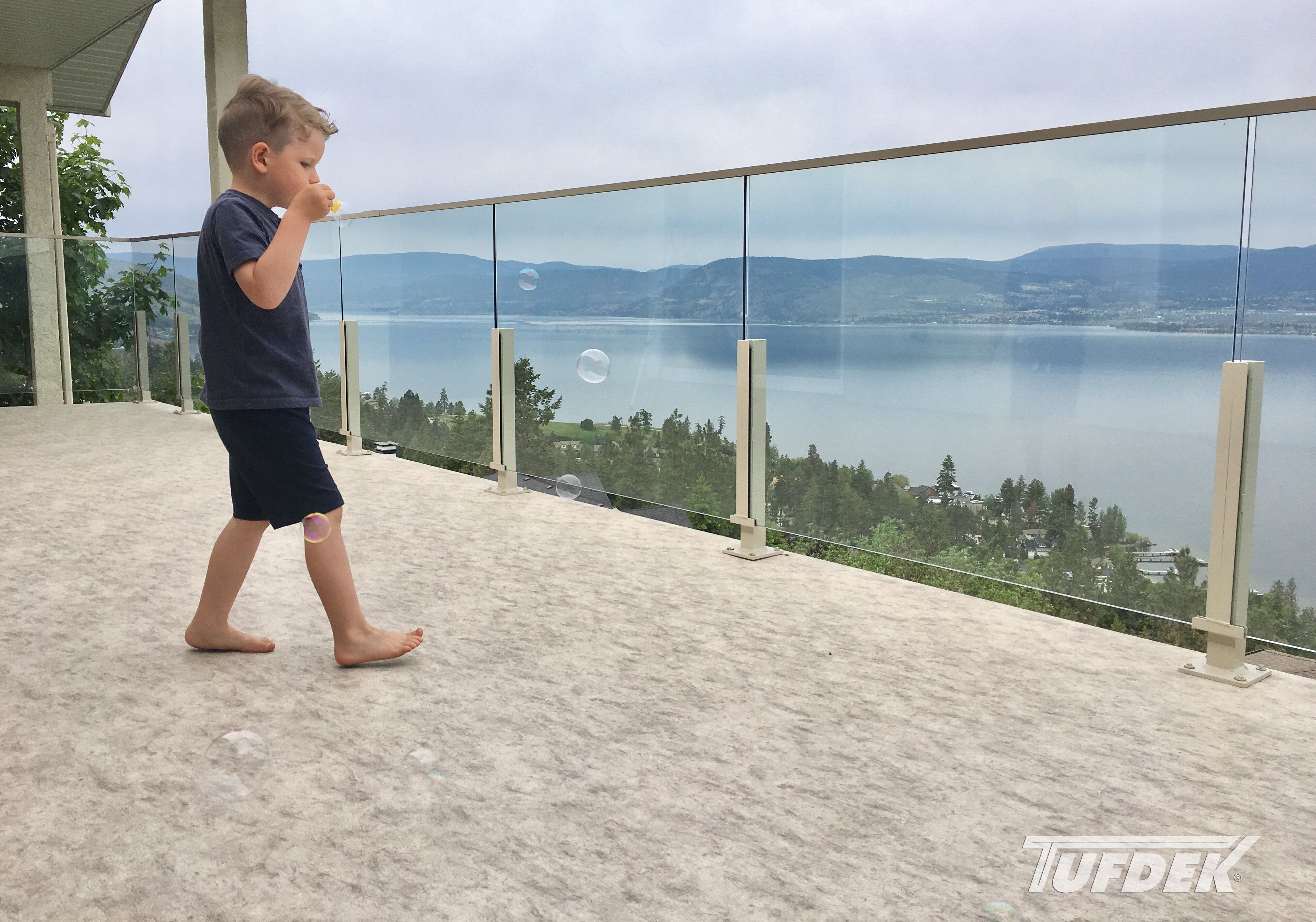 TUFDEK OUTDOOR VINYL FLOORING Barefoot child blowing bubbles on newly installed balcony vinyl flooring