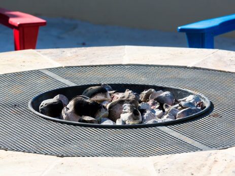 Concrete fire pit with a red bench and blue bench in the background