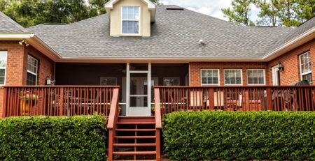 Wooden stairs leading from back lawn up to a large backyard deck