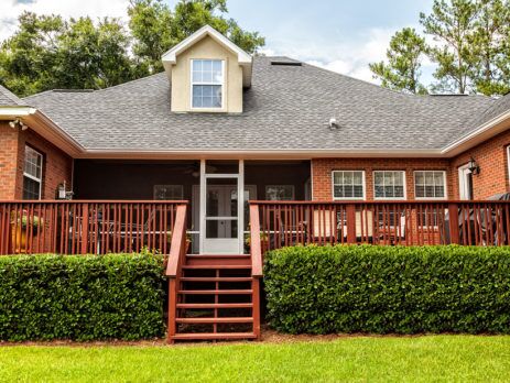 Wooden stairs leading from back lawn up to a large backyard deck