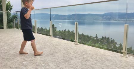 Barefoot child blowing bubbles on newly installed balcony vinyl flooring