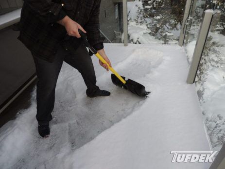 Man shovelling snow off a vinyl deck