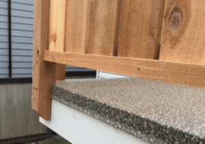 Aggregate waterproof vinyl decking showing finished deck edge and wooden railing.